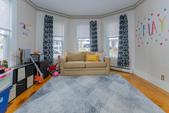 sitting room with hardwood / wood-style floors, a baseboard heating unit, and crown molding