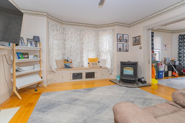 interior space featuring a wood stove, ornamental molding, and wood-type flooring