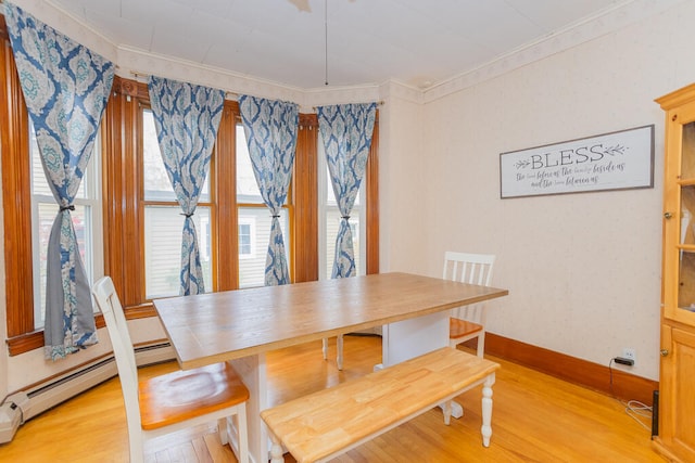 dining area featuring crown molding, baseboard heating, and light wood-type flooring