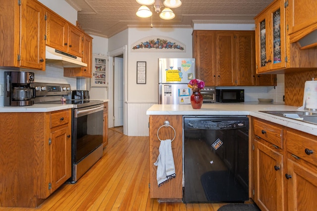 kitchen featuring tasteful backsplash, black appliances, ornamental molding, light hardwood / wood-style flooring, and a chandelier