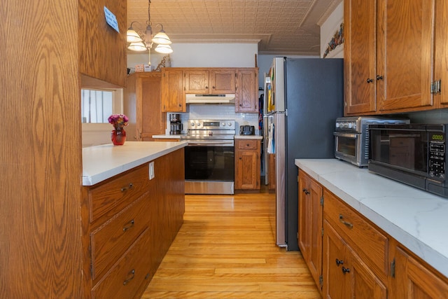 kitchen with appliances with stainless steel finishes, backsplash, light hardwood / wood-style floors, pendant lighting, and a chandelier