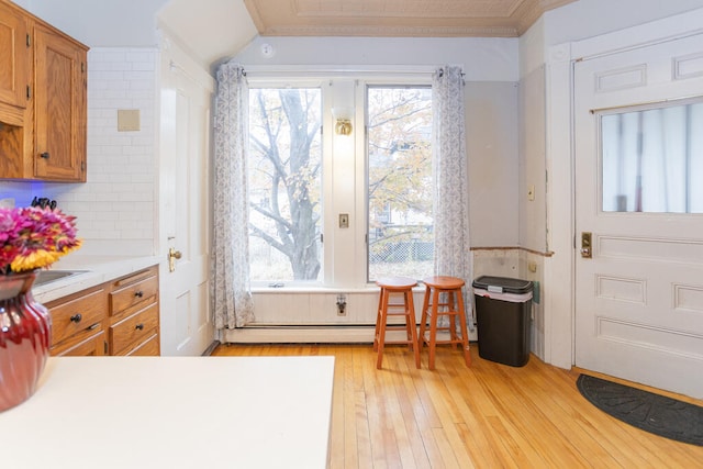 interior space with ornamental molding, decorative backsplash, light hardwood / wood-style flooring, and a baseboard heating unit