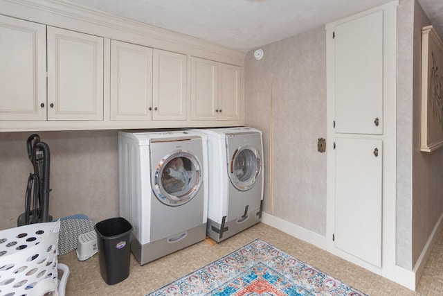 laundry area with separate washer and dryer and cabinets