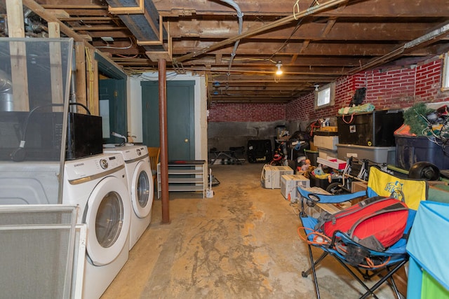 basement featuring independent washer and dryer and brick wall