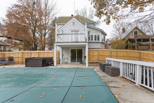 back of property featuring a balcony, a swimming pool with hot tub, and a patio area