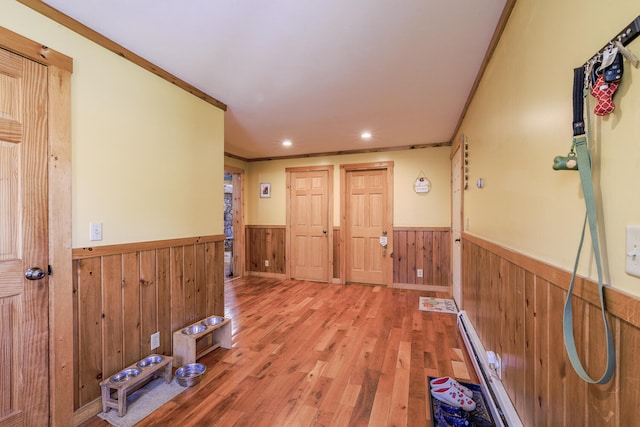 corridor featuring crown molding, light hardwood / wood-style flooring, and wooden walls