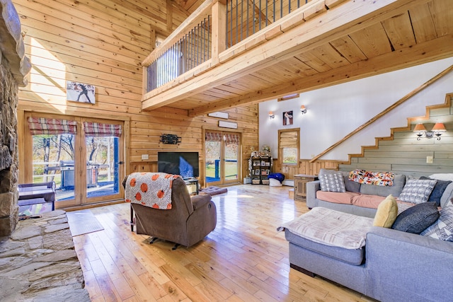 living room featuring beam ceiling, high vaulted ceiling, light hardwood / wood-style flooring, and wood walls