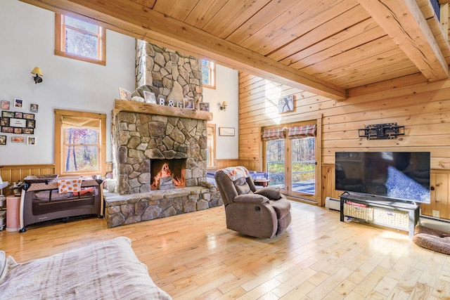 living room featuring beamed ceiling, a high ceiling, light wood-type flooring, and wood walls