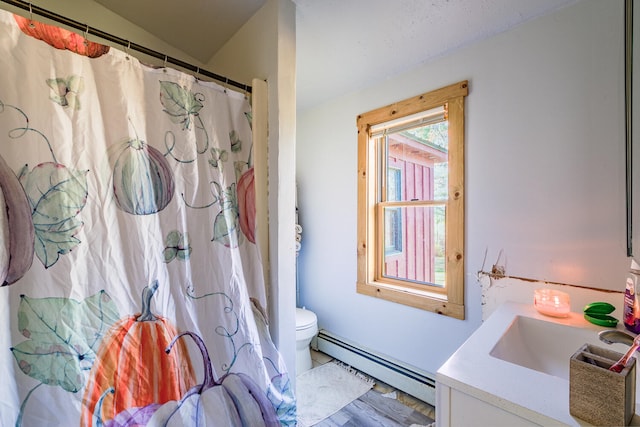 bathroom featuring vanity, a baseboard heating unit, and toilet