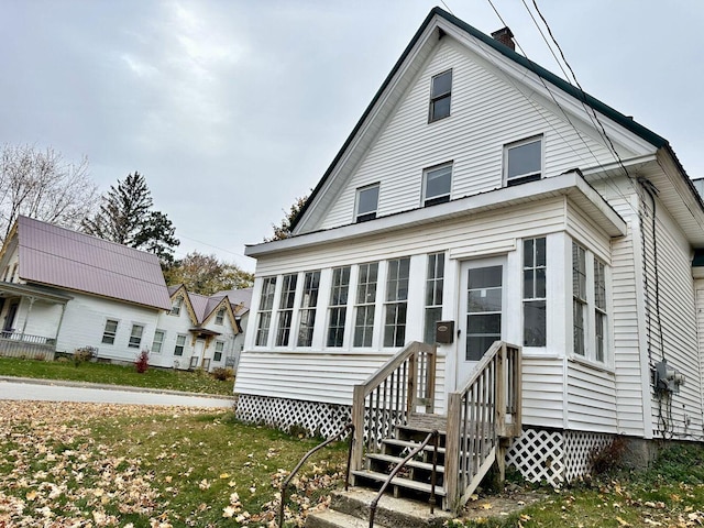 rear view of house featuring a yard and a sunroom