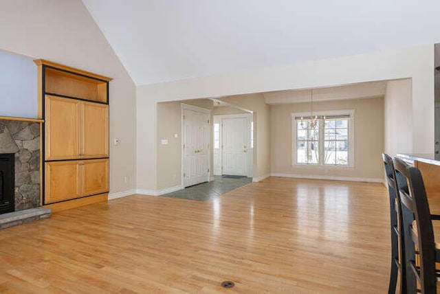 unfurnished living room with high vaulted ceiling, a fireplace, and light hardwood / wood-style floors