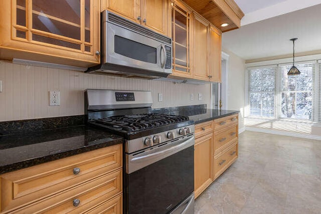 kitchen featuring stainless steel appliances, hanging light fixtures, and dark stone countertops