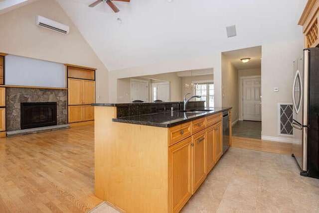 kitchen featuring sink, ceiling fan, appliances with stainless steel finishes, a wall mounted AC, and a stone fireplace