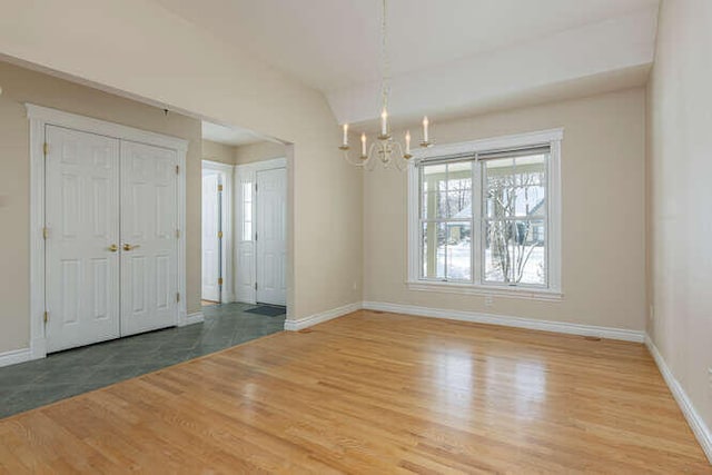 entrance foyer with lofted ceiling, wood-type flooring, and a chandelier