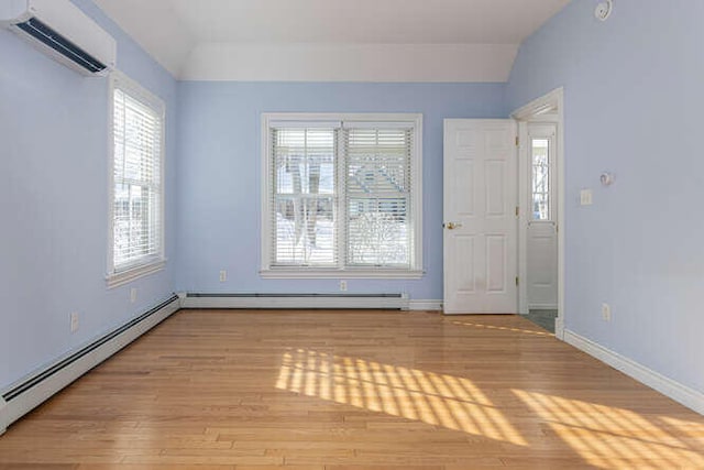 entrance foyer with light hardwood / wood-style floors, lofted ceiling, a wall unit AC, and baseboard heating