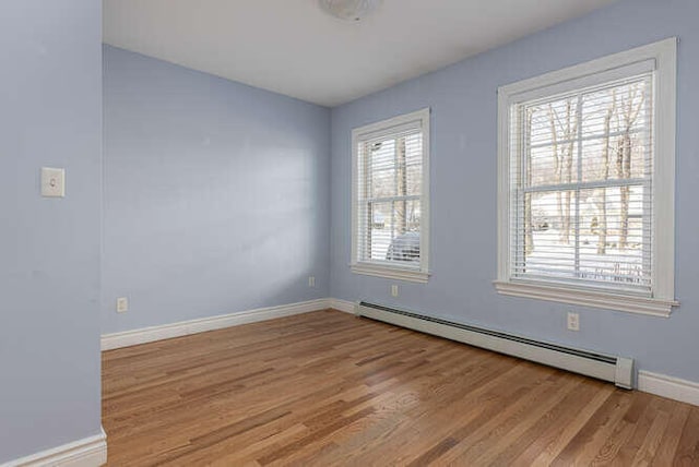 spare room with baseboard heating and light hardwood / wood-style flooring