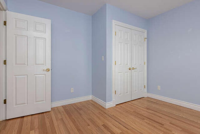 unfurnished bedroom with light hardwood / wood-style floors and a closet