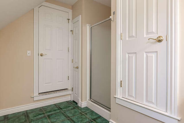 bathroom with tile patterned flooring, lofted ceiling, and a shower with shower door