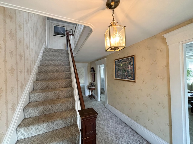 staircase featuring a notable chandelier and carpet