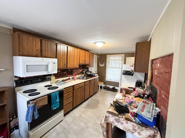 kitchen featuring backsplash, sink, crown molding, and white appliances