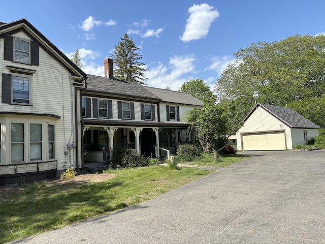 view of front of home with a front yard, an outdoor structure, and a garage