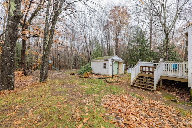 view of yard with a wooden deck, a storage shed, and a playground