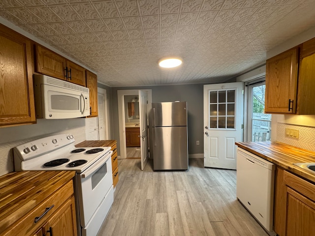 kitchen with white appliances, light hardwood / wood-style floors, and wood counters