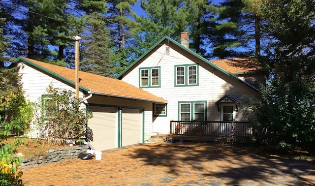 back of property with a wooden deck and a garage