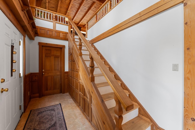 stairs with wood walls, beamed ceiling, and wooden ceiling