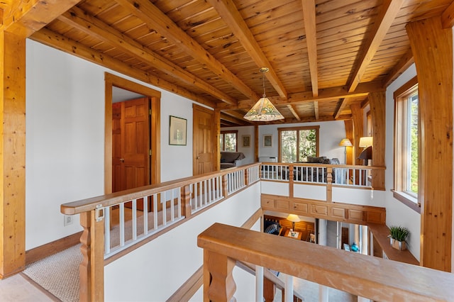 stairs featuring plenty of natural light, beam ceiling, and wood ceiling