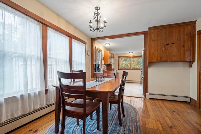 dining area featuring light hardwood / wood-style floors, baseboard heating, and a chandelier