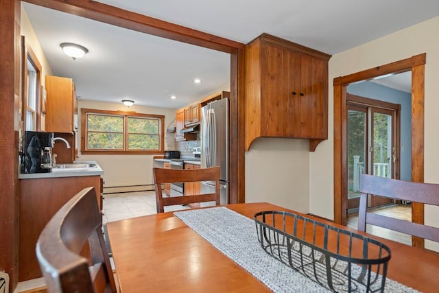 dining space with light tile patterned flooring, baseboard heating, plenty of natural light, and sink