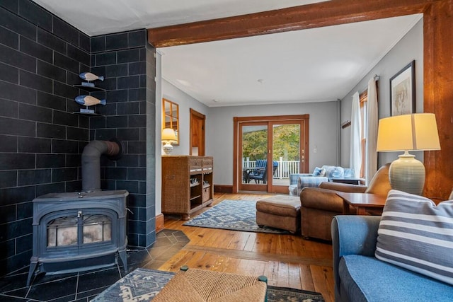 living room featuring wood-type flooring, a wood stove, crown molding, and beam ceiling