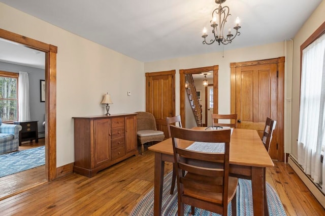 dining area featuring light hardwood / wood-style floors, a baseboard radiator, and a notable chandelier