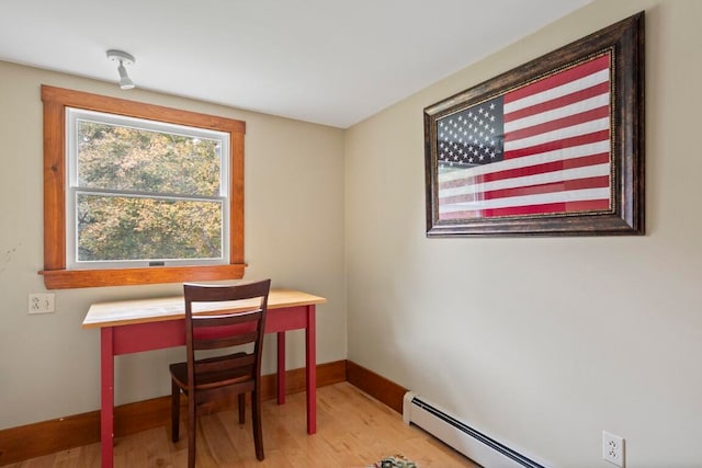 home office with light hardwood / wood-style floors and a baseboard heating unit