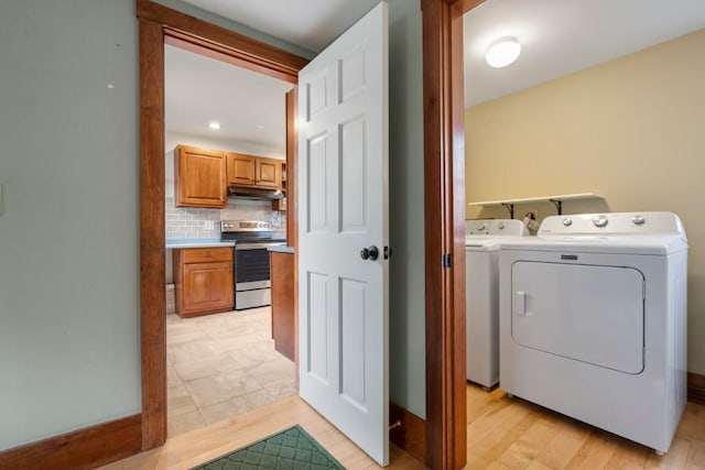 clothes washing area with light hardwood / wood-style floors and washing machine and clothes dryer