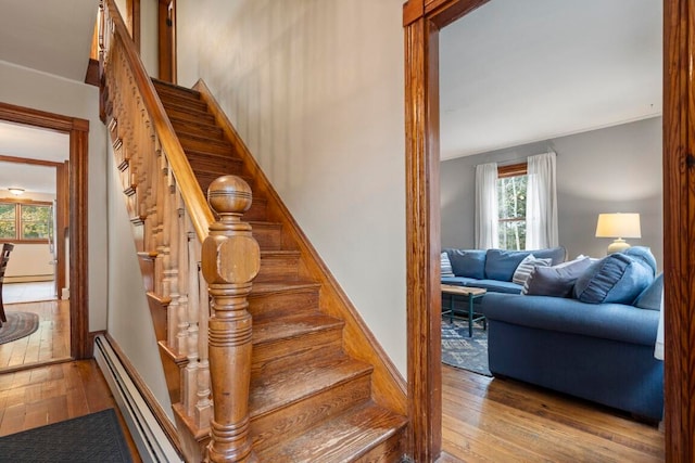 stairs featuring hardwood / wood-style floors and a baseboard heating unit