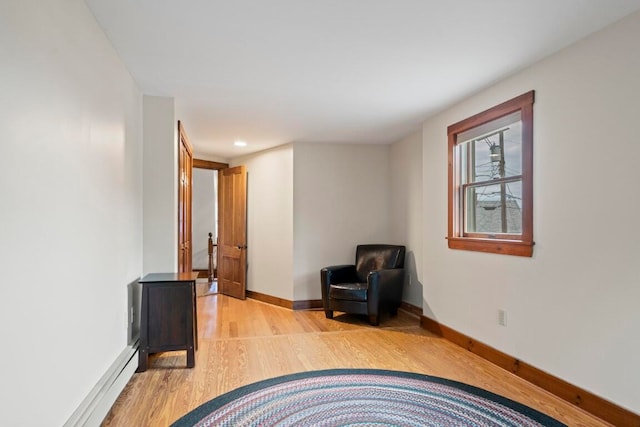 living area with baseboard heating and light hardwood / wood-style flooring