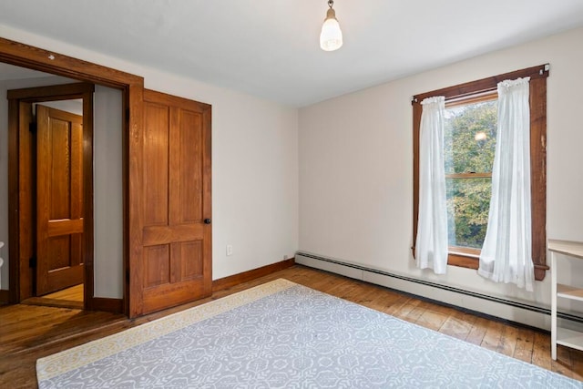 unfurnished bedroom featuring hardwood / wood-style floors and a baseboard radiator