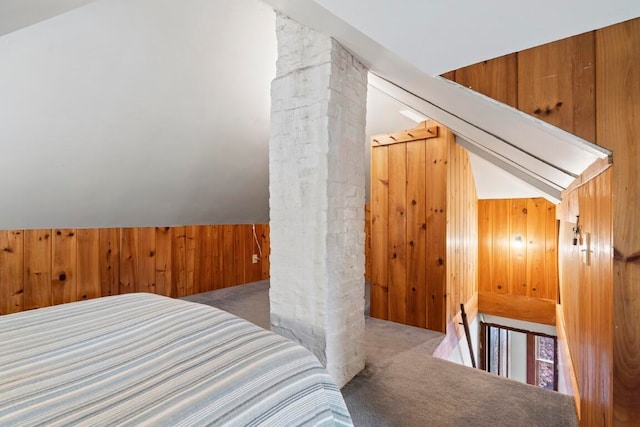 carpeted bedroom featuring decorative columns, vaulted ceiling, and wood walls