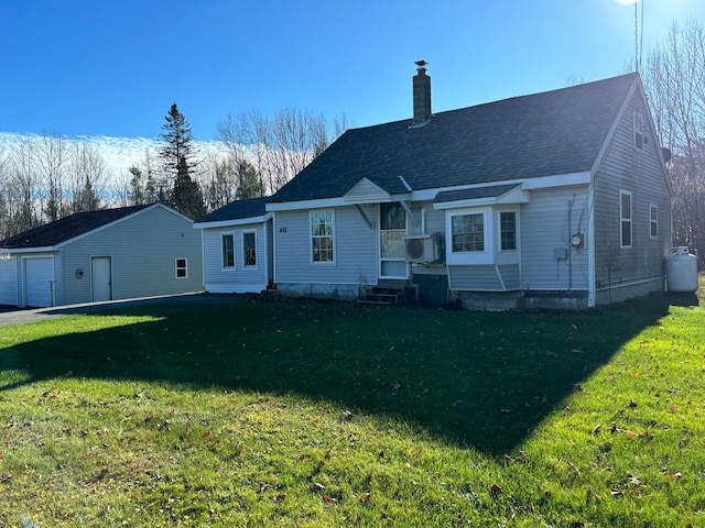 back of property featuring a garage, a lawn, and an outdoor structure