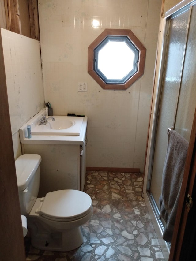 bathroom with toilet, vanity, and a shower with door