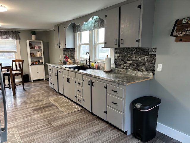 kitchen with light hardwood / wood-style flooring, decorative backsplash, sink, and plenty of natural light