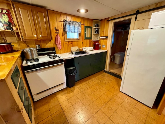 kitchen with wood walls, a barn door, sink, and white appliances