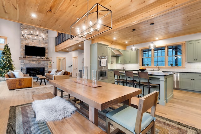 dining space with light hardwood / wood-style floors, a healthy amount of sunlight, wooden ceiling, and a fireplace