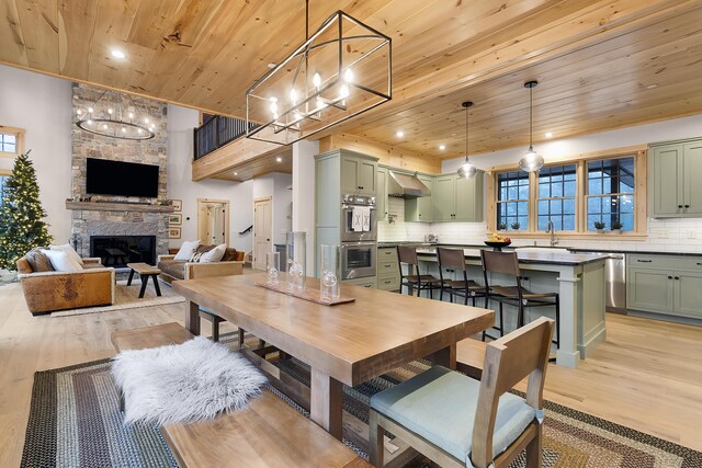 100 Morganite Way, Newry, ME 04261 - dining area featuring a chandelier, wooden ceiling, light wood finished floors, a stone fireplace, and healthy amount of natural light