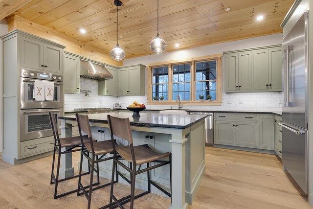 100 Morganite Way, Newry, ME 04261 - kitchen featuring stainless steel appliances, wooden ceiling, wall chimney range hood, a kitchen breakfast bar, and a sink