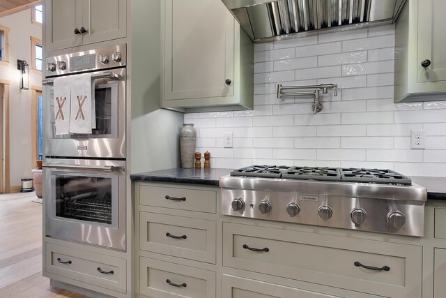 100 Morganite Way, Newry, ME 04261 - kitchen featuring appliances with stainless steel finishes, wall chimney range hood, decorative backsplash, and light wood-style flooring