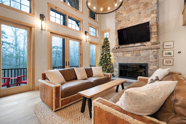 living room with french doors, a fireplace, light wood-type flooring, and a towering ceiling