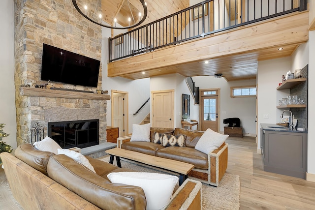 100 Morganite Way, Newry, ME 04261 - living room featuring stairway, light wood finished floors, a towering ceiling, a stone fireplace, and wooden ceiling